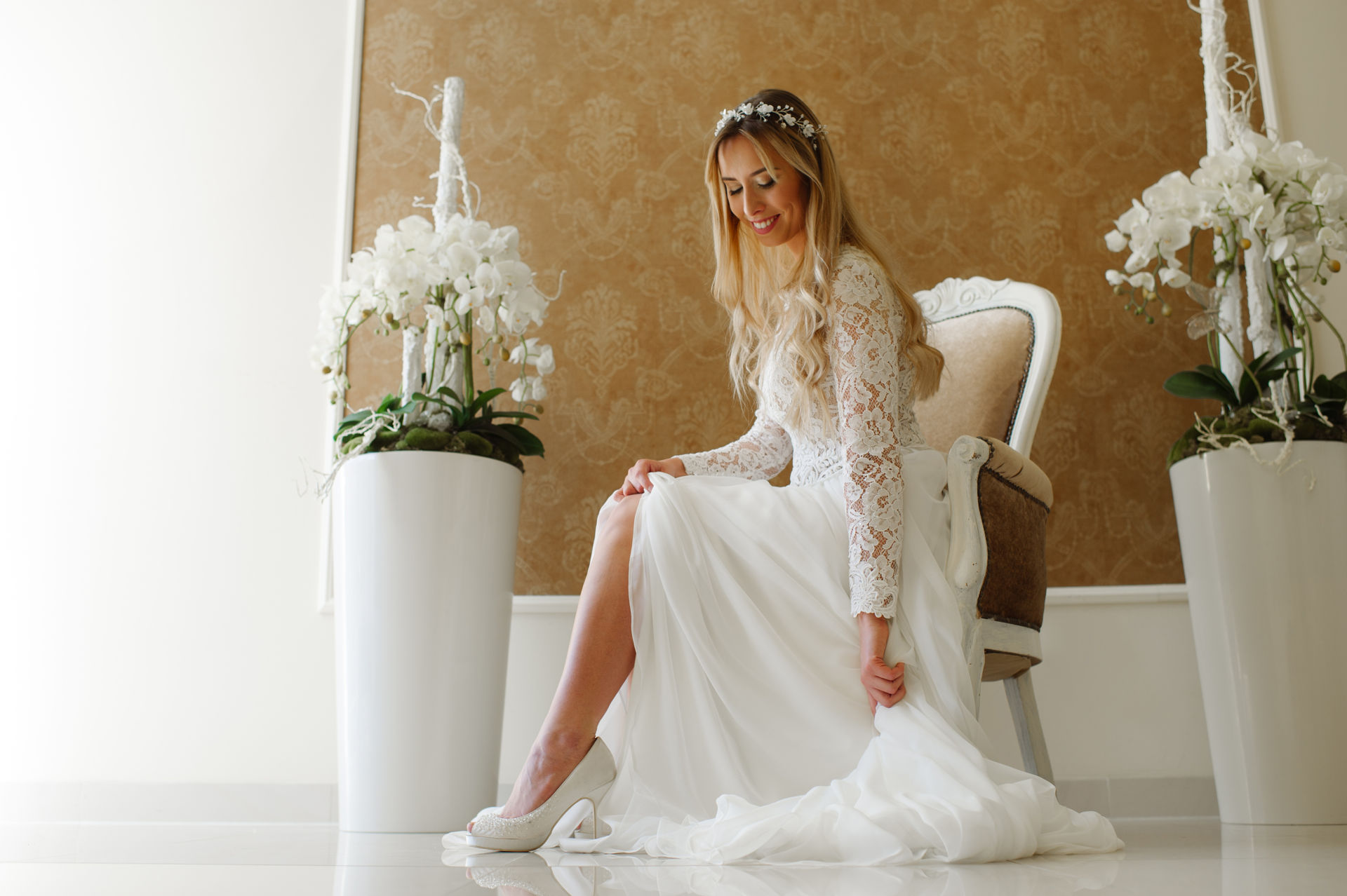 Modelka w sukni ślubnej siedzaca na stylowym krześle